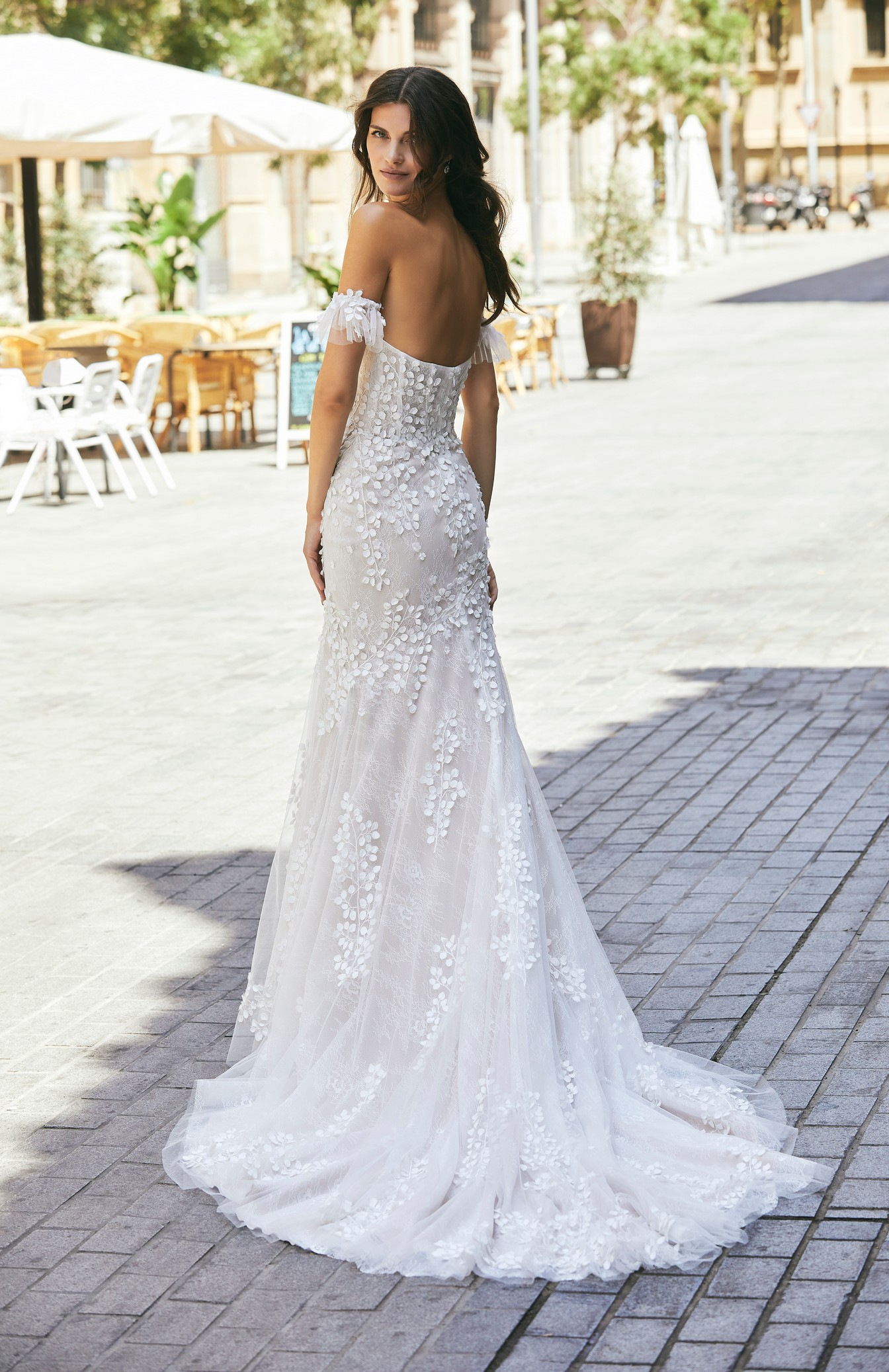 Back profile of model wearing Ronald Joyce wedding dress style 18616, a strapless lace wedding dress with feminine floral applique detailing and detachable illusion sleeves 