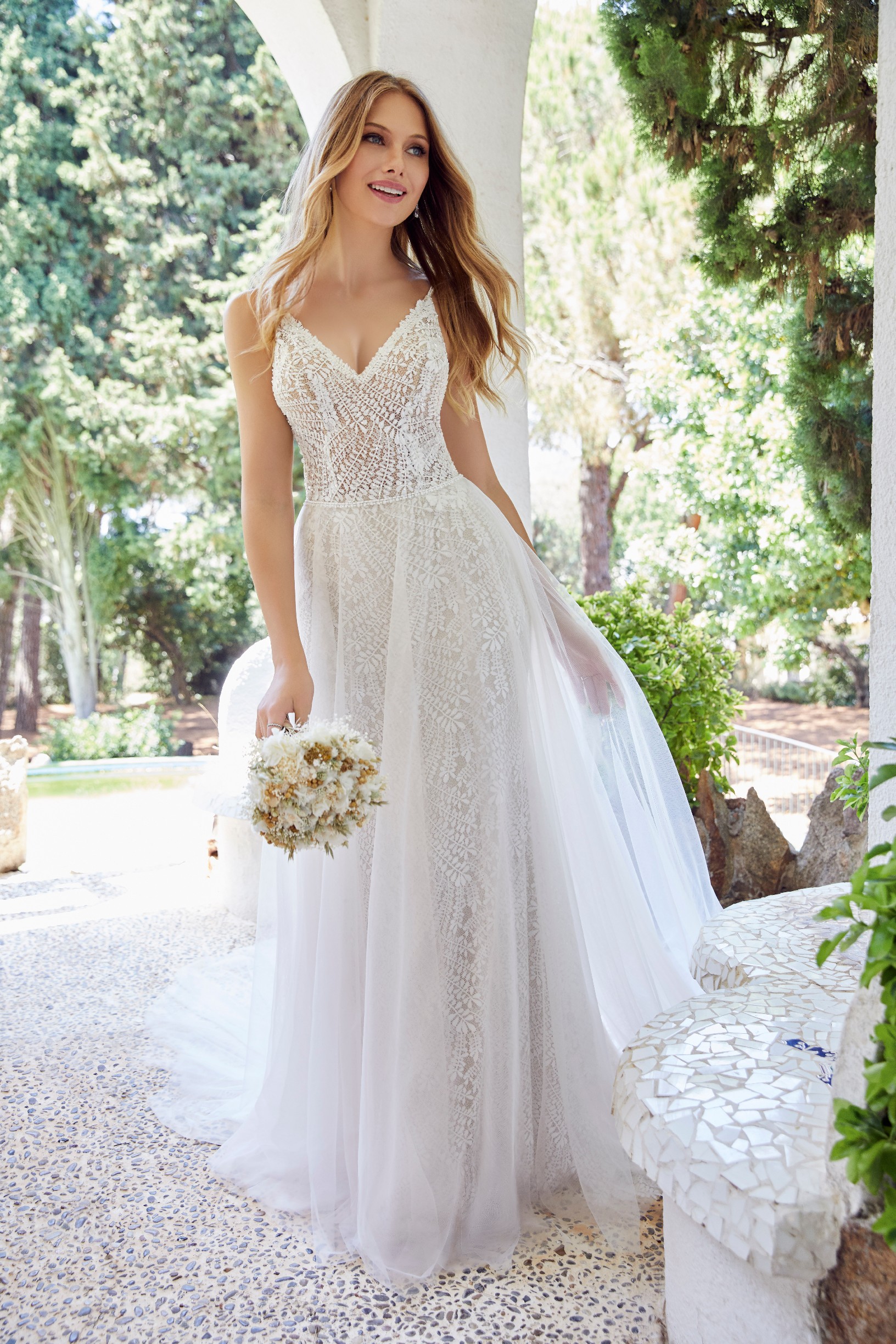 Close up of a bride stood in woodland wearing a white wedding dress with long sheer detachable pearl-beaded blouson sleeves