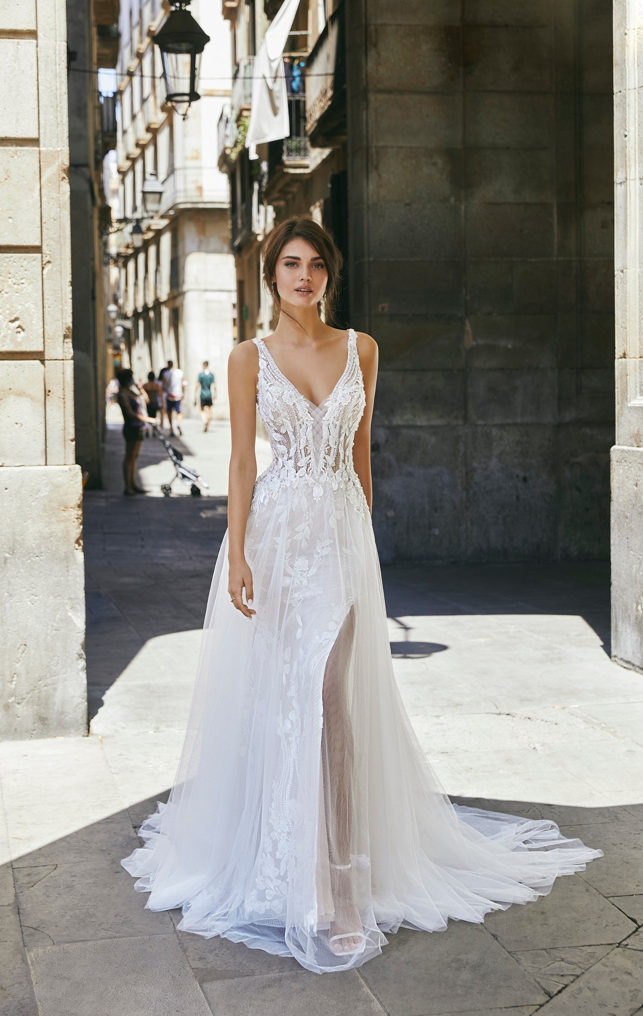 Front profile of model wearing Ronald Joyce style 69701, a striking A-line lace wedding dress with straps, an illusion v-neckline and tulle skirt.