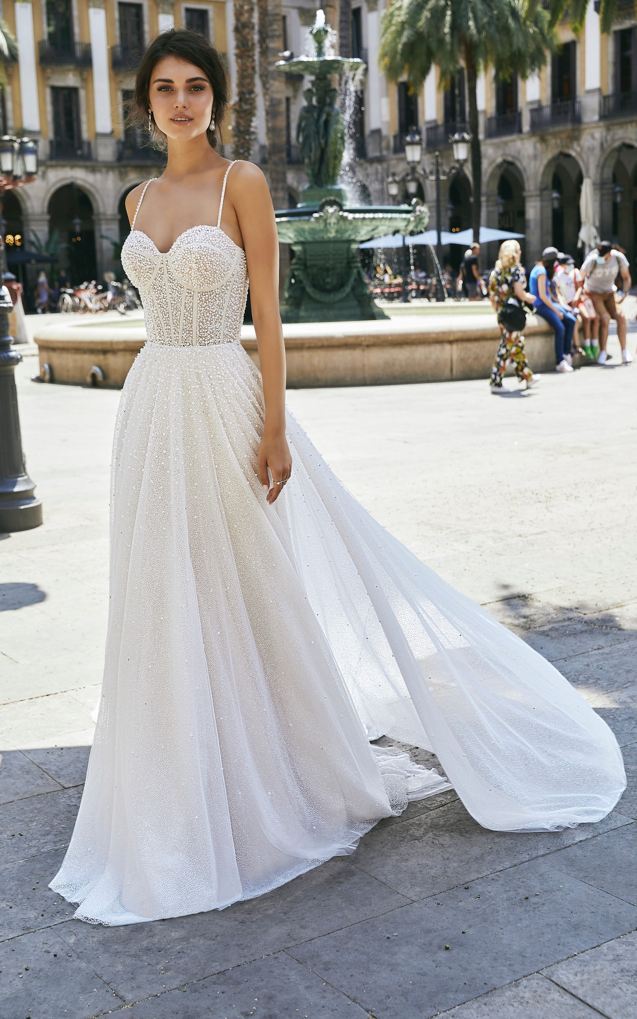 Front profile of model wearing Ronald Joyce wedding dress style 69712, an exquisitely pearl-beaded fit and flare gown in glitter tulle with delicate straps and a sweetheart neckline. Model wears matching tulle overskirt (69712B) and colour ivory and champagne. 