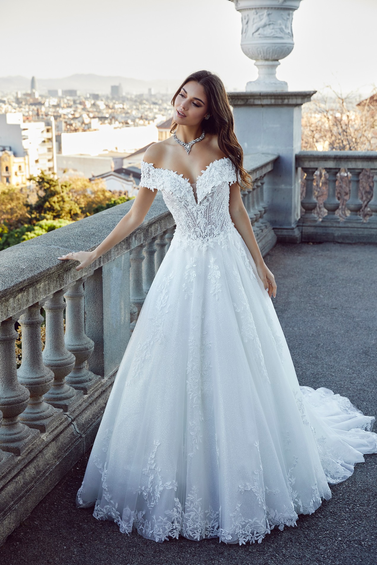 Woman in white wedding dress standing next to stone balcony 