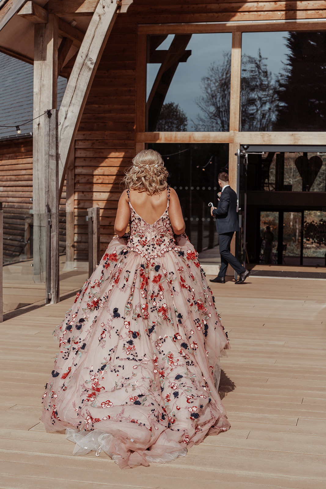 A rear profile photo of our Ronald Joyce real bride, Rebecca, in her Celestina wedding dress, a blush ballgown with colourful floral appliques. 