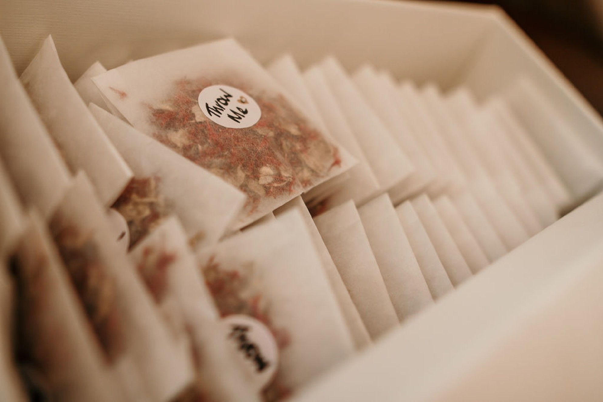 A neatly-packed box of wedding confetti parcels with a round label saying throw me.jpg